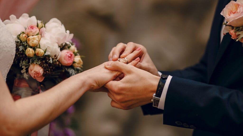 A bride and groom exchanging wedding rings during a heartfelt ceremony accompanied by one of the top Christian wedding songs, creating a profoundly meaningful moment.